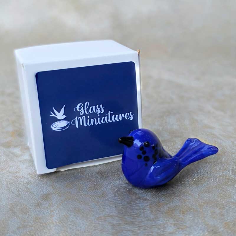 The Chic Nest handblown blue glass wren miniature figurine displayed next to its small white gift box.